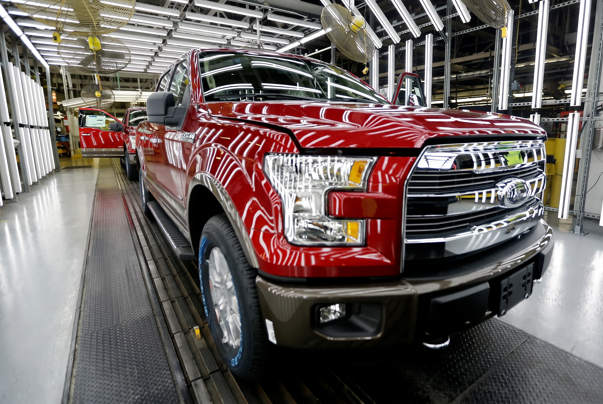Red pickup truck on a factory assembly line under bright overhead lights